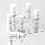 Collection of skincare products from D' Lumiere Esthetique on a reflective surface with a light gray background.